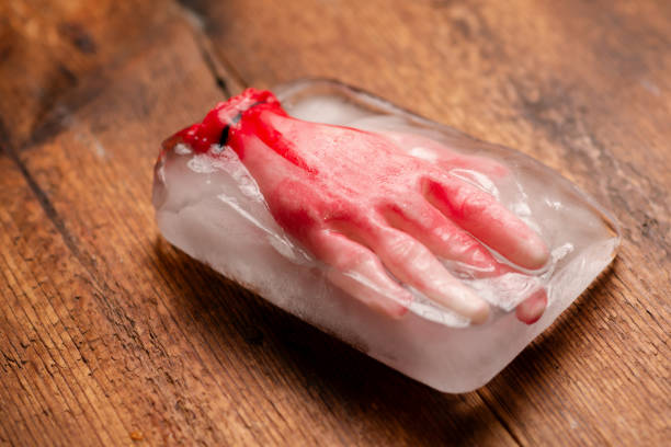 Frozen terror: A Halloween concept with an artificial human hand frozen in a block of ice on a wooden surface, evoking a sense of frozen terror and suspense Frozen terror: A Halloween concept with an artificial human hand frozen in a block of ice on a wooden surface, evoking a sense of frozen terror and suspense suspenseful stock pictures, royalty-free photos & images