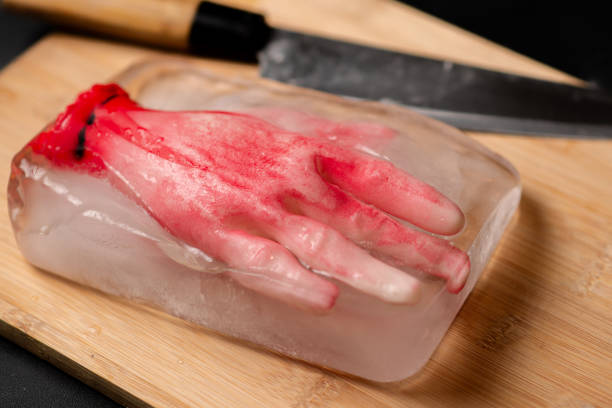 Icy terror: A horror concept with a model human hand frozen within a piece of ice on a wooden cutting board, creating a bone-chilling and unsettling composition Icy terror: A horror concept with a model human hand frozen within a piece of ice on a wooden cutting board, creating a bone-chilling and unsettling composition suspenseful stock pictures, royalty-free photos & images