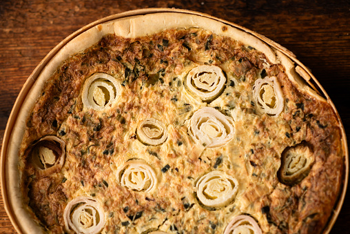 Flavorsome Creation: A beautifully baked leek and egg pie, arranged on a wooden table, captivates with its savory allure