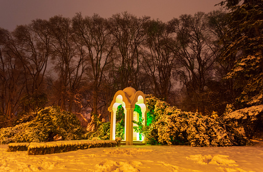 Green illuminated Sea Garden park  covered with snow at winter night Varna city Bulgaria