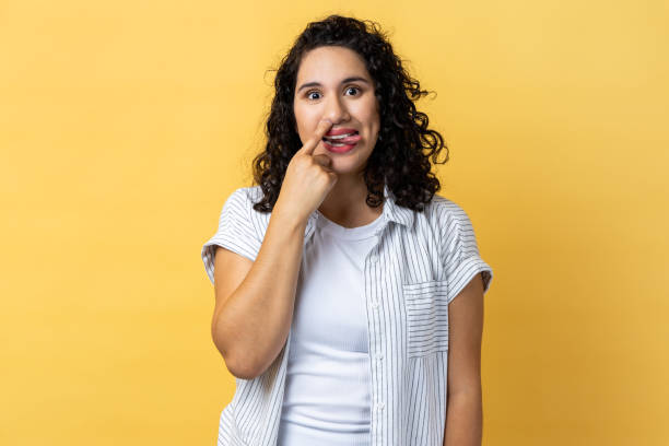 femme debout, se curant le nez et tirant la langue avec une expression comique stupide, s’amusant. - poking nose in photos et images de collection