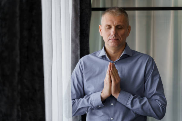 istock A man stands near the window doing relaxing breathing exercises. 1814918127
