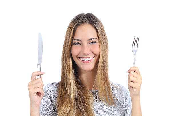 hermosa mujer sostiene un tenedor y cuchillo - tasting women eating expressing positivity fotografías e imágenes de stock