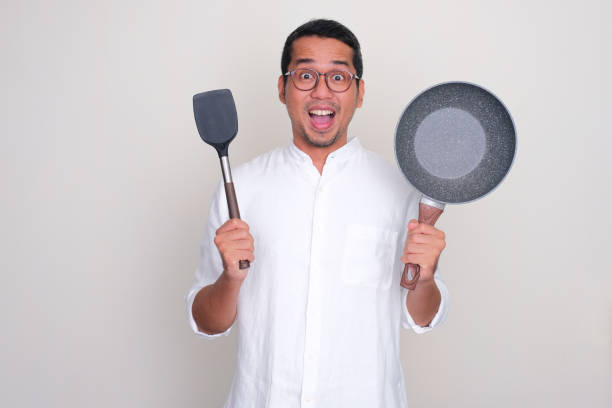 istock Adult Asian man showing wow expression while holding frying pan and spatula 1814927639