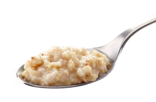 Spoon of oats porridge on a white background