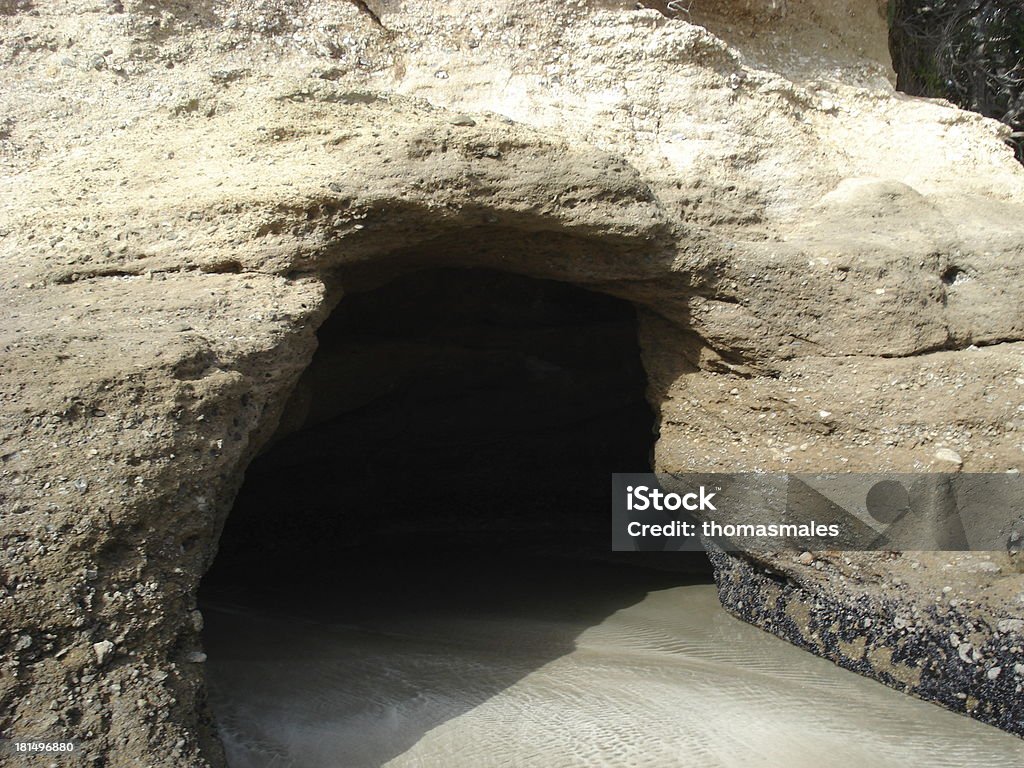 Seaside residence A cave in a rock wall by the ocean with a sand floor, carpeted by the sea. Accessibility Stock Photo