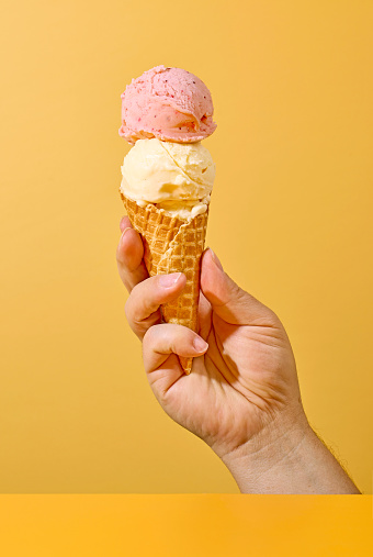 ice cream in human hand on yellow background