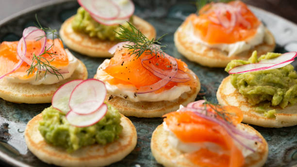 istock Mini blini pancakes with soft cheese, cold smoked salmon and guacamole 1815017190