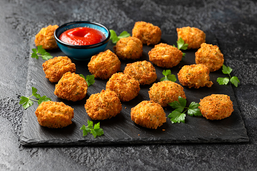 Potato croquettes with ham and cheese on stone board.