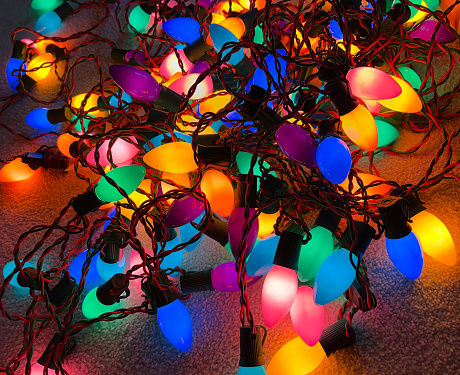 Large pile of glowing Christmas holiday lights tangled up.