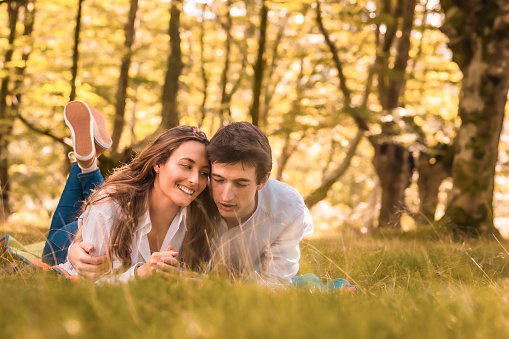 Horizontal photo with copy space of a romantic scene of a couple lying together in the forest