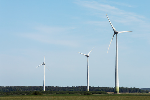 View of wind turbines and agriculture field in blue sky background.