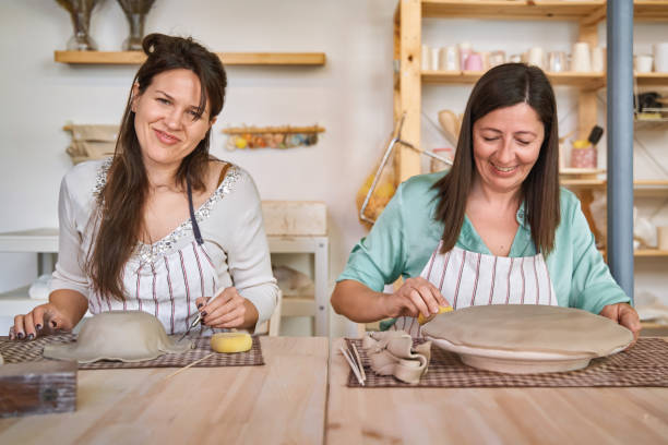 istock Two women in aprons smiling while enjoying together in a ceramic workshop. 1815055242