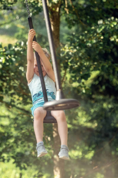 istock A small boy from the front on a rope swing coming towards us at high speed, a dusty background of green trees 1815058017