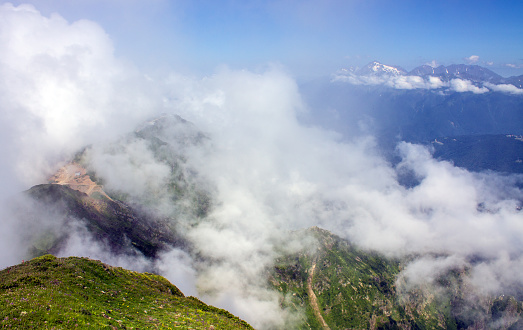 Dramatic landscape - white clouds among the peaks of the mountains against the blue sky on a sunny day and a space to copy