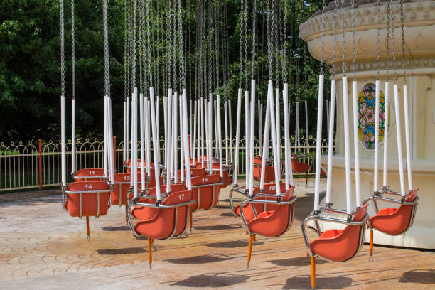 Retro carousel on chains not working with empty seats on a sunny summer day at an amusement park in Sochi Olympic village