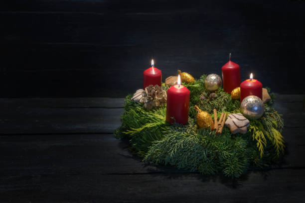 istock Light in the dark on third advent, natural green wreath with red candles, three are burning, Christmas decoration and cookies, dark wooden background, copy space 1815066691