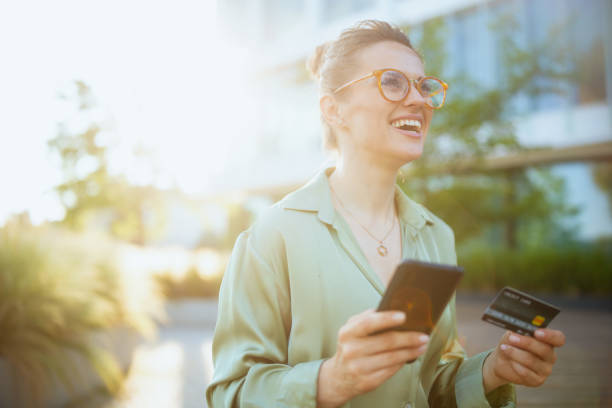 happy female worker in green blouse and eyeglasses using phone