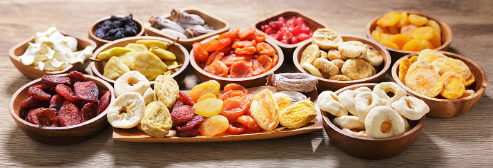 Wooden spoons with healthy seeds, nuts and dried fruits arranged on wooden table