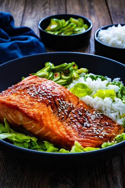 istock Seared teriyaki salmon steak with black and white rice on wooden table 1815102925