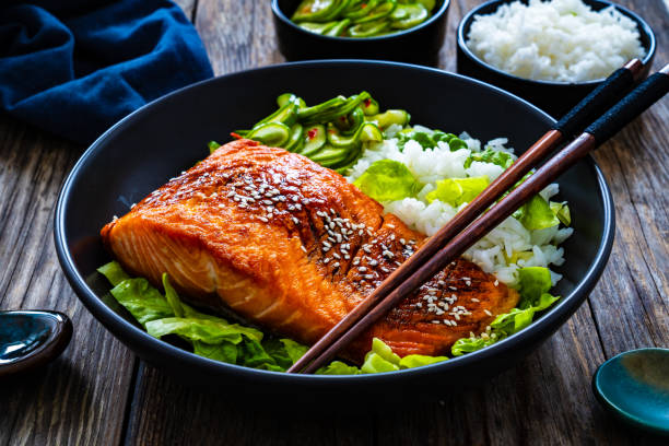 istock Seared teriyaki salmon steak with black and white rice on wooden table 1815103301