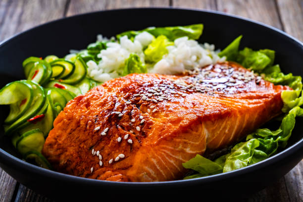 istock Seared teriyaki salmon steak with black and white rice on wooden table 1815103312