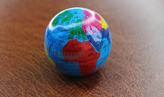 Miniature globe on a leather surface with conventionally drawn continents