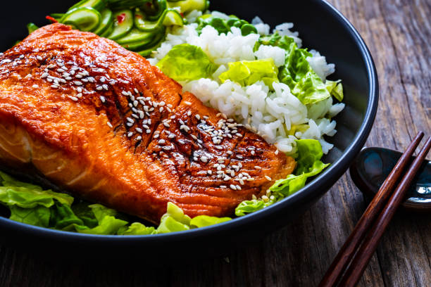 istock Seared teriyaki salmon steak with black and white rice on wooden table 1815103820