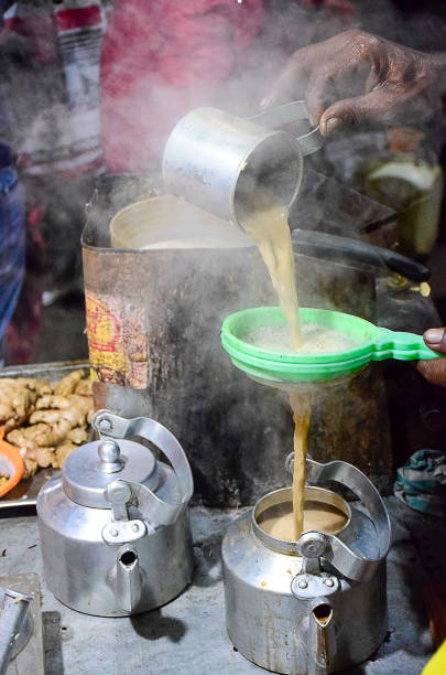 istock Tea maker hand pouring milk tea in pot after sieving with plastic sieve with another kettle by the side in Odisha, India, Asia,12.02.2020. 1815106252