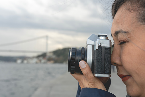 The woman takes pictures of the beautiful Istanbul view with an analog camera. woman takes photos on 35 mm film.
