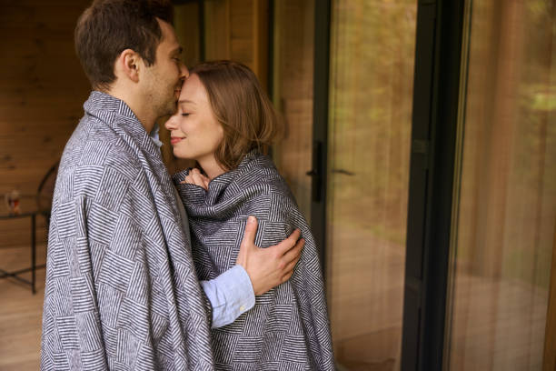 istock Cute lovely couple covered in blanket embracing 1815130188