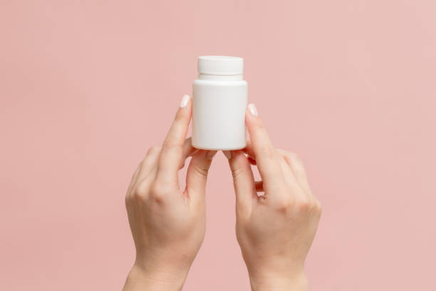 istock White bottle (plastic tube) in hands on pink background. Packaging for vitamins, pill or capsule, or supplement. Mockup for product branding 1815153266