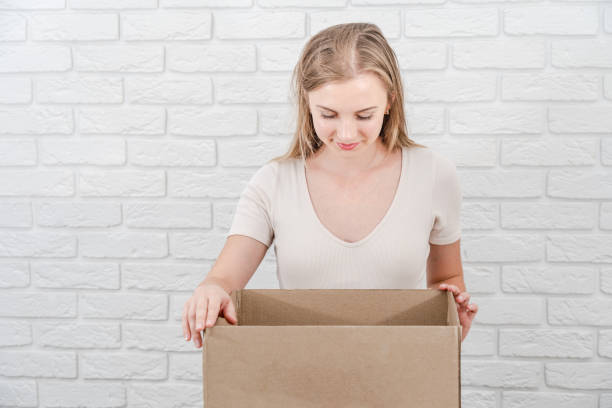istock Attractive blonde woman with open cardboard box. Delivering a parcel 1815157556