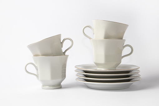 White coffee cups and saucers with a gold brim on a white background