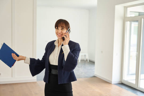 istock Woman real estate agent communicates on her mobile phone in spacious empty room 1815168766
