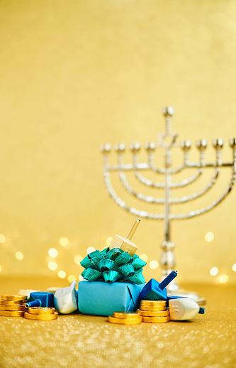 Hanukkah background with chocolate gelt and gift. Dreidel and menorah with copy space