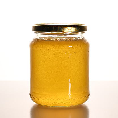 Jar with acacia honey  on white background