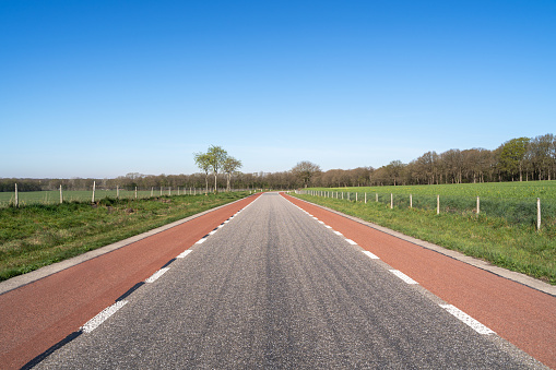 Rural asphalt road with red bicycle lanes in the netherlands