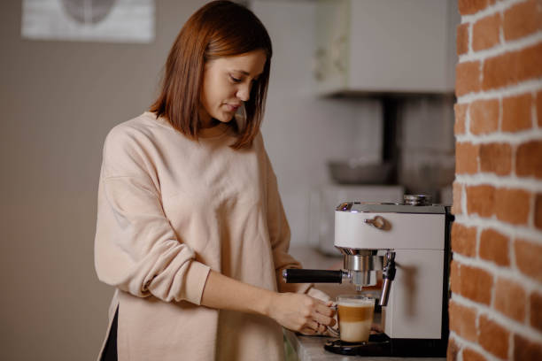 istock Beautiful woman preparing coffee in coffee machine at home 1815197963