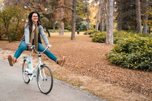 istock Cheerful young woman cycling on the path in public park 1815201148