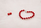 Red jewelry: bracelet and earrings with beads on a white background. The Concept Of Valentine's Day
