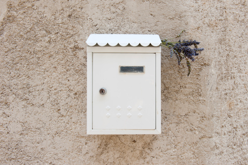 White mailbox on beige stucco wall in a box bouquet of lavender