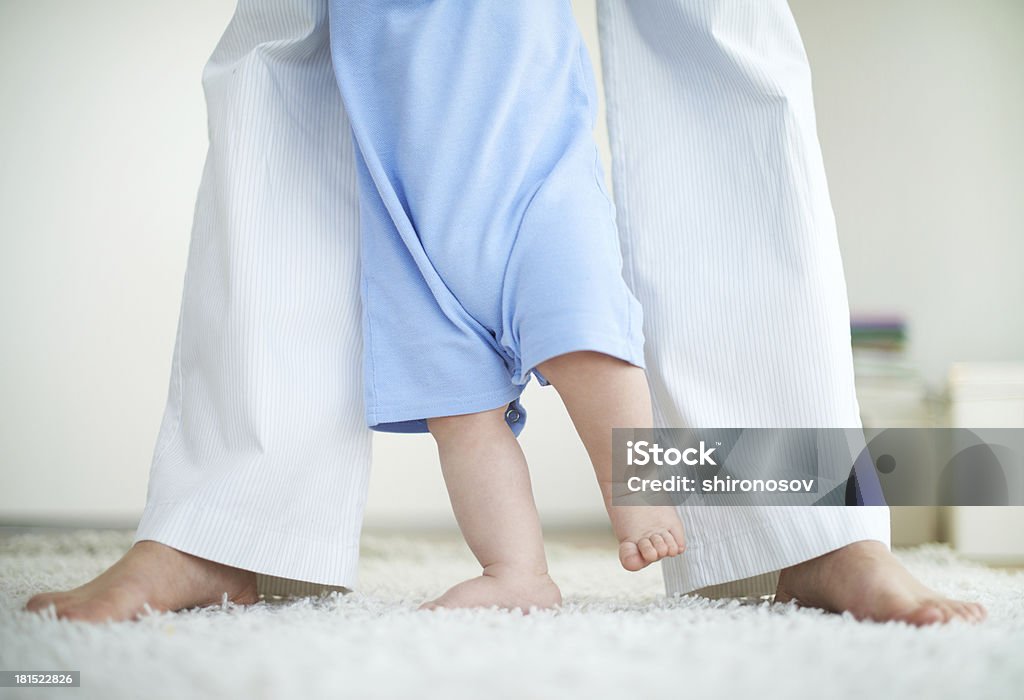 Learning to walk Close-up of female and little baby legs during walk down the floor Activity Stock Photo