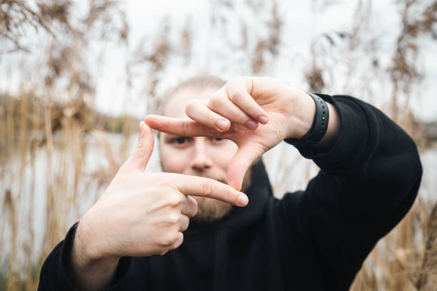 istock A young man looking through finger frame on natural reeds background. 1815243395