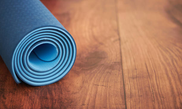 istock Rolled up blue yoga mat on a wood floor with space for text 1815249186