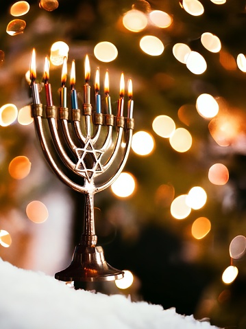 Hanukkah celebration with menorah, gift box and dreidel on wooden table over blackboard background