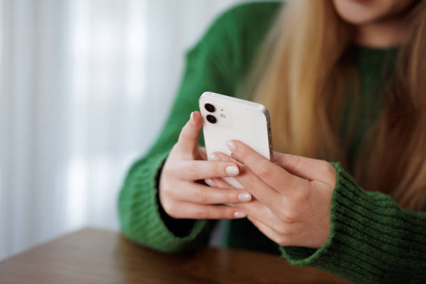 istock a young girl writes a message on the phone while sitting at the table, working online, chatting 1815252363