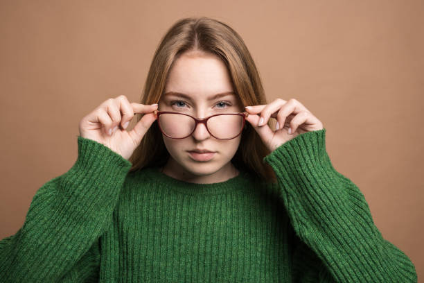 istock woman with poor vision on a isolated beige background, health problems astigmatism myopia, Poor vision concept 1815253414