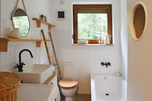 Small interior of bathroom with bathroom sink, toilet and window in a cottage. Home decor. Architecture indoors.