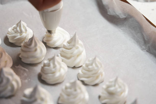 istock Close up of female hands using piping bag to make maringue cookies before baking 1815261242